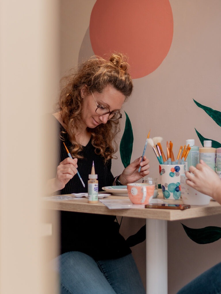 Client s'adonnant à la peinture sur céramique dans notre café artistique à Rouen